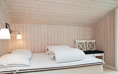 a white room with two beds and a table at Holiday Home Pandrup 07 in Pandrup