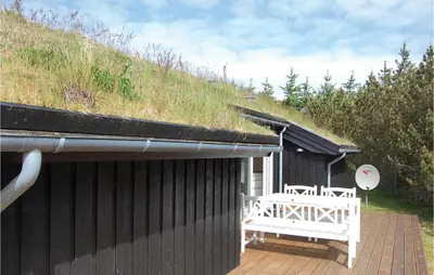 a black house with a white bench on a deck at Holiday Home Pandrup 07 in Pandrup