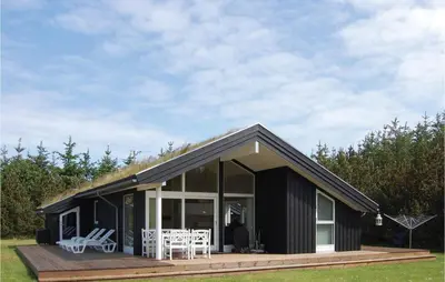 a black house with a deck and chairs on it at Holiday Home Pandrup 07 in Pandrup