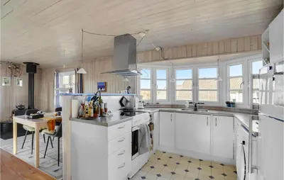 a large kitchen with white cabinets and a table at Holiday Home Frøstrup With Fireplace 10 in Frøstrup