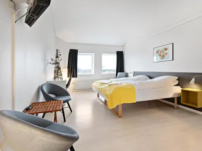 a bedroom with two beds and a chair at Løgstør Parkhotel in Løgstør