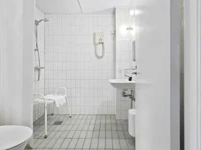 a white bathroom with a sink and a shower at Løgstør Parkhotel in Løgstør