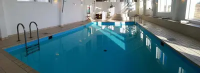 a large swimming pool with blue water in a building at Løgstør Parkhotel in Løgstør