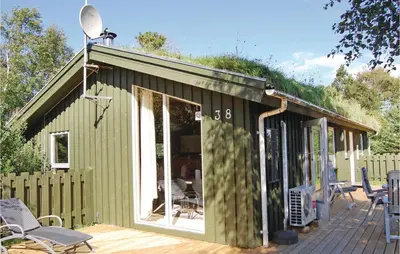 a green building with a deck with chairs at Holiday Home Pandrup With Hot Tub V in Pandrup