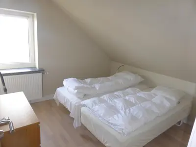 a bedroom with a bed with white sheets and a window at Harboøre Hotel in Harboør