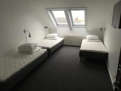 a room with three beds and a window at Danhostel Thyborøn in Thyborøn