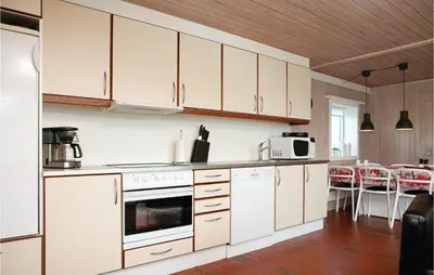 a kitchen with white cabinets and a table and chairs at Holiday Home Pandrup With Fireplace Ii in Pandrup
