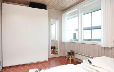 a bedroom with a bed and two windows at Holiday Home Pandrup With Fireplace Ii in Pandrup
