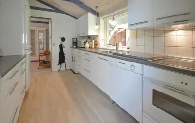 a kitchen with white cabinets and a wooden floor at Holiday Home Hurup Thy With Hot Tub I in Sønder Ydby