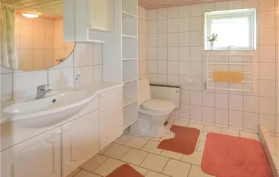 a bathroom with a toilet and a sink and a mirror at Holiday Home Veslos With Fireplace I in Højstrup