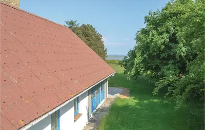 a building with a red roof next to a tree at Holiday Home Veslos With Fireplace I in Højstrup