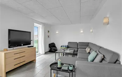 a living room with a couch and a flat screen tv at Klitrosen in Harboør