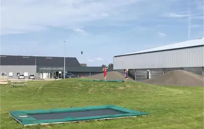 two people standing in a field with a trampoline at Klitrosen in Harboør