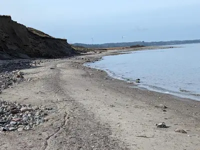 a beach with rocks and water on a sunny day at 7 person holiday home in Løgstør-By Traum in Trend