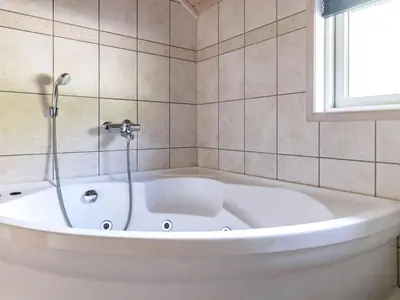 a white bath tub in a bathroom with a window at 7 person holiday home in Løgstør-By Traum in Trend