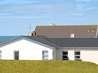a white house with a black roof and the ocean at 6 person holiday home in Lemvig-By Traum in Ferring