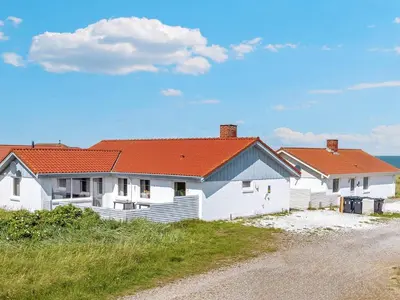 a white house with an orange roof on a beach at 8 person holiday home in Frøstrup-By Traum in Lild Strand