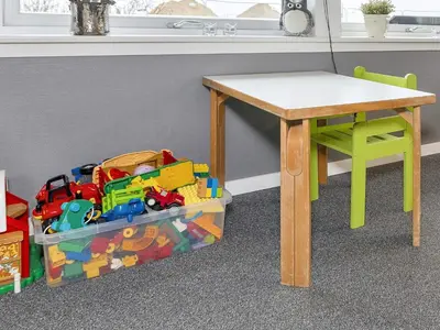 a table and a chair next to a table and a pile of toys at 8 person holiday home in Løgstør-By Traum in Trend