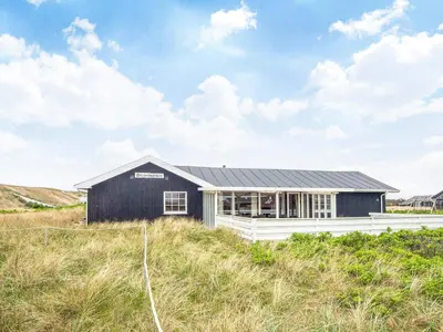a black house on top of a grassy hill at 12 person holiday home in Harboøre-By Traum in Vrist