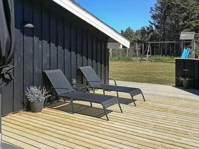 two chairs on a wooden deck with a playground at 9 person holiday home in Løkken-By Traum in Grønhøj