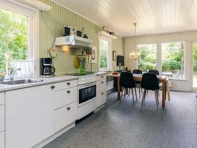 a kitchen with white cabinets and a table with chairs at 2 person holiday home in Thyholm-By Traum in Thyholm