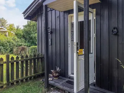 a black tiny house with a porch and a door at 2 person holiday home in Thyholm-By Traum in Thyholm