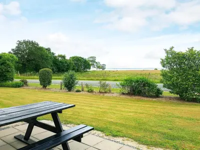 a wooden picnic table in a park with a field at 5 person holiday home in Roslev-By Traum in Sønder Thise