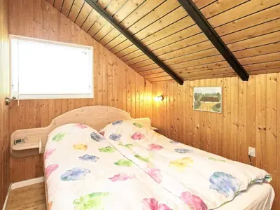 a bed in a room with wooden walls and a window at 6 person holiday home in Saltum-By Traum in Saltum