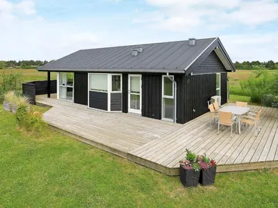 a black cabin with a table on a wooden deck at Bright Beach House Retreat - By Traum Ferienwohnungen in Trudslev