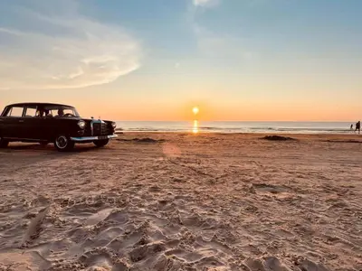 an old car parked on the beach at sunset at 6 person holiday home in Saltum-By Traum in Saltum