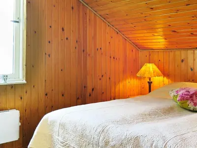 a bedroom with wooden walls and a bed with a lamp at Seaside Retreat with Sauna - By Traum Ferienwohnungen in Vrist