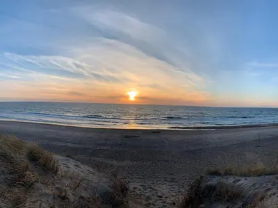 a sunset on a beach with the ocean at Seaside Retreat with Sauna - By Traum Ferienwohnungen in Vrist
