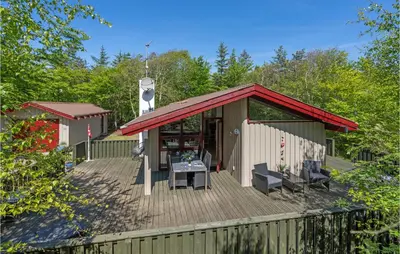 a building with a deck with a table and chairs at Holiday Home Saltum Doggerbanke in Saltum