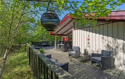 a wooden deck with chairs and a bird cage at Holiday Home Saltum Doggerbanke in Saltum