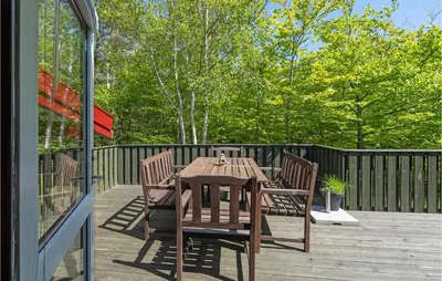 a wooden table and chairs on a deck at Holiday Home Saltum Doggerbanke in Saltum