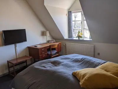 a bedroom with a bed and a desk and a window at Sevel Kro in Vinderup