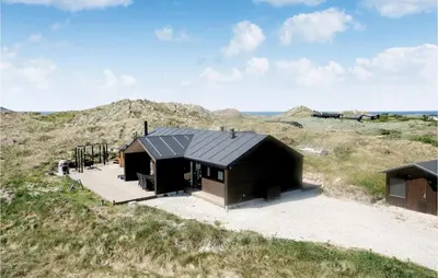 a small black house in the middle of a field at Studio Holiday Home In Lokken in Løkken