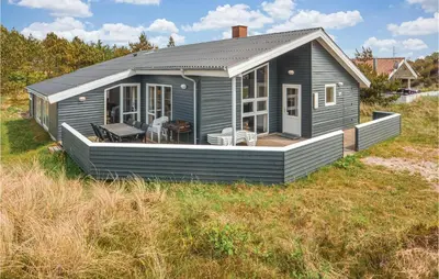 a grey house with a deck on a field at Four-Bedroom Holiday Home In Thisted in Thisted