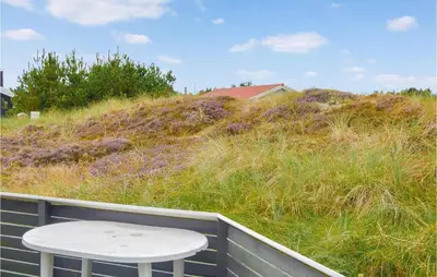 a white stool sitting on a fence next to a grassy hill at Four-Bedroom Holiday Home In Thisted in Thisted