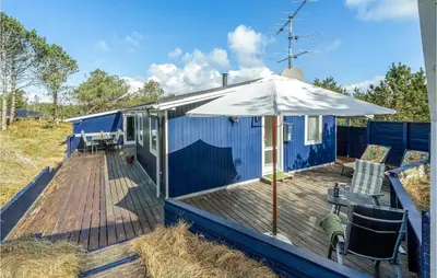 a blue tiny house with an umbrella on a deck at Two-Bedroom Holiday Home In Thisted in Thisted