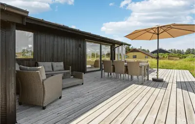a wooden deck with chairs and an umbrella at Three-Bedroom Holiday Home In Thisted in Nørre Vorupør