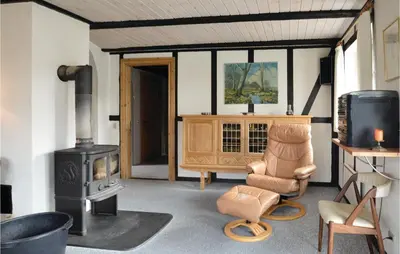 a living room with a wood stove and a chair at Three-Bedroom Holiday Home In Spottrup in Spottrup
