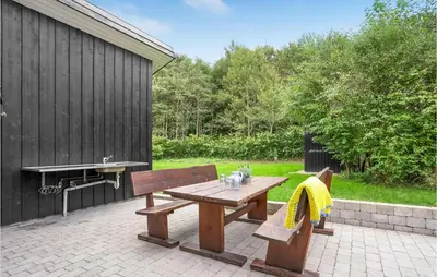 a picnic table and bench on a brick patio at Three-Bedroom Holiday Home In Skals in Skals