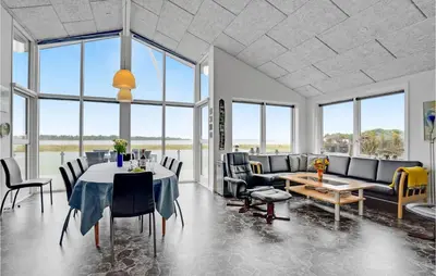 a dining room with a table and chairs and windows at Three-Bedroom Holiday Home In Skals in Skals