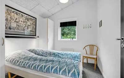 a bedroom with a bed and a chair and a window at Three-Bedroom Holiday Home In Skals in Skals