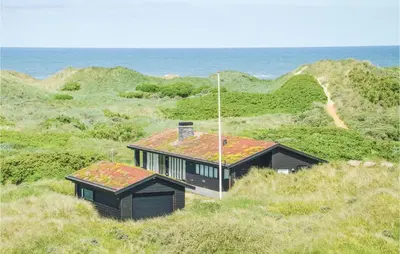 a house sitting on top of a hill near the ocean at Stunning Home In Løkken With Kitchen in Løkken