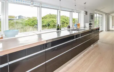 a kitchen with a large counter with windows at Stunning Home In Løkken With Kitchen in Løkken