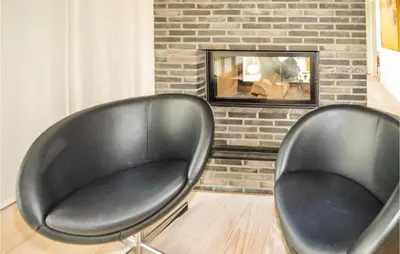 two black leather chairs in front of a fireplace at Stunning Home In Løkken With Kitchen in Løkken