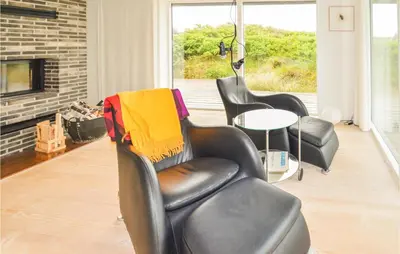 a salon with two chairs and a table and a fireplace at Stunning Home In Løkken With Kitchen in Løkken