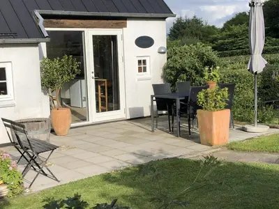 a patio with a table and chairs and an umbrella at Heltoften Bed & Breakfast in Nykøbing Mors